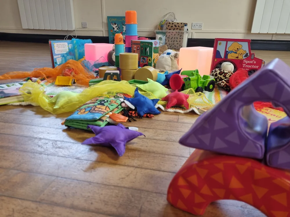 Bright scarves, fabric stars, light cubes and books arranged for sensory discovery