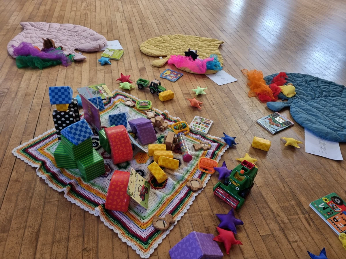 Individual leaf-shaped play mats arranged around a colourful shared collection of toys and books